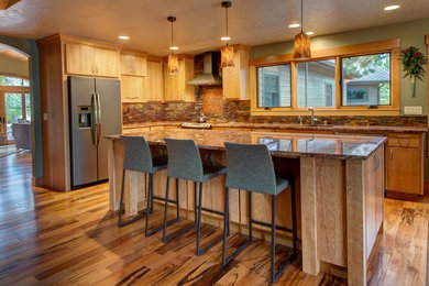 Enclosed kitchen - mid-sized craftsman l-shaped light wood floor enclosed kitchen idea in Orange County with an undermount sink, flat-panel cabinets, light wood cabinets, granite countertops, multicolored backsplash, stone tile backsplash, stainless steel appliances and an island
