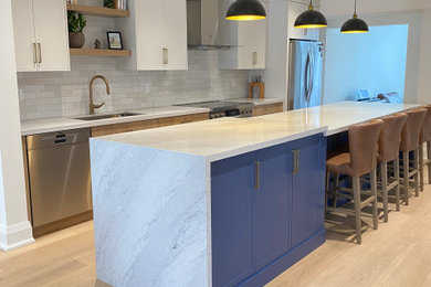 Eat-in kitchen - mid-sized contemporary galley light wood floor eat-in kitchen idea in Toronto with an undermount sink, flat-panel cabinets, quartz countertops, white backsplash, porcelain backsplash and an island