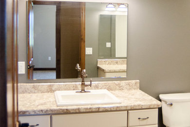 Bathroom - mid-sized traditional 3/4 medium tone wood floor bathroom idea in Other with raised-panel cabinets, white cabinets, granite countertops, a two-piece toilet, gray walls and a drop-in sink