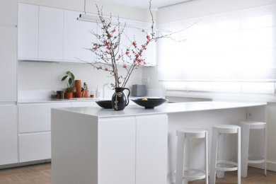 Modelo de cocina contemporánea abierta con puertas de armario blancas, encimera de acrílico, salpicadero blanco, una isla y encimeras blancas