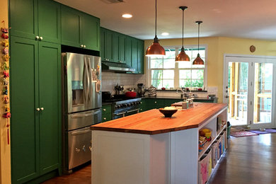 Large trendy l-shaped medium tone wood floor and brown floor eat-in kitchen photo in Austin with a farmhouse sink, shaker cabinets, green cabinets, wood countertops, white backsplash, subway tile backsplash, stainless steel appliances and an island