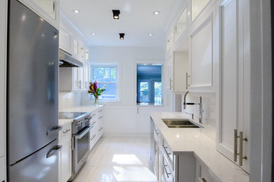 Example of a mid-sized trendy galley marble floor and white floor enclosed kitchen design in Toronto with a double-bowl sink, glass-front cabinets, white cabinets, quartz countertops, white backsplash, stone slab backsplash, stainless steel appliances and no island