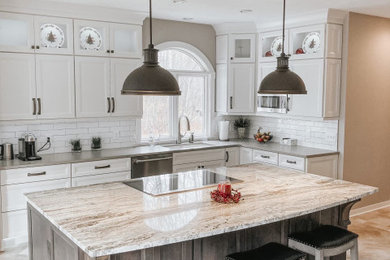 Inspiration for a large timeless porcelain tile and beige floor eat-in kitchen remodel in Grand Rapids with an undermount sink, recessed-panel cabinets, white cabinets, granite countertops, white backsplash, ceramic backsplash, stainless steel appliances, an island and multicolored countertops