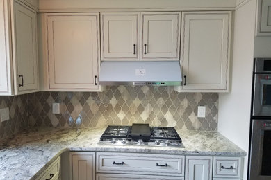 Example of a large french country l-shaped cement tile floor and beige floor eat-in kitchen design in Other with an undermount sink, beaded inset cabinets, white cabinets, granite countertops, beige backsplash, glass tile backsplash, stainless steel appliances, an island and multicolored countertops