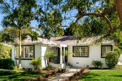 Example of a mid-sized trendy white one-story stucco house exterior design in Los Angeles with a hip roof and a shingle roof