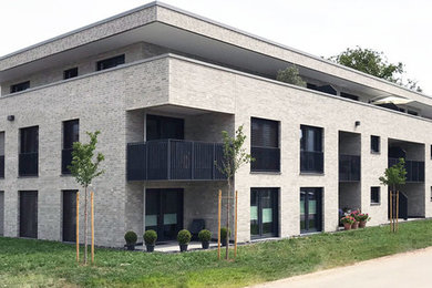 Große, Dreistöckige Moderne Dachbegrünung mit Backsteinfassade, grauer Fassadenfarbe und Flachdach in Hannover