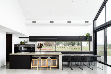 Photo of an expansive contemporary galley eat-in kitchen in Hobart with an integrated sink, black cabinets, concrete benchtops, window splashback, black appliances, concrete floors and with island.