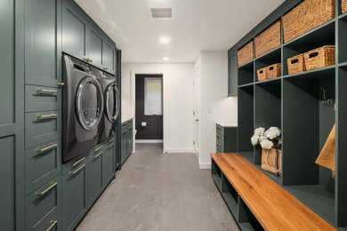 Large laundry room photo in Seattle with green cabinets and a side-by-side washer/dryer