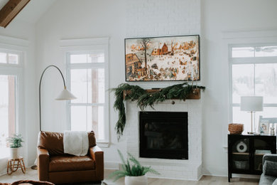 Example of a country laminate floor and exposed beam living room design in Other with white walls, a standard fireplace and a brick fireplace