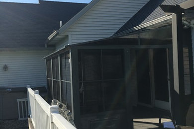 Example of a large backyard deck design in Grand Rapids with a roof extension