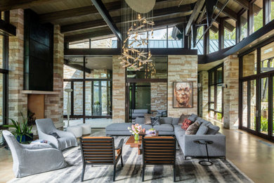 Inspiration for a large contemporary concrete floor, brown floor and exposed beam living room remodel in Denver with beige walls, a standard fireplace and a stone fireplace