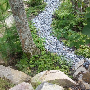 This is an example of a mid-sized traditional front yard partial sun garden in Portland Maine with river rock.
