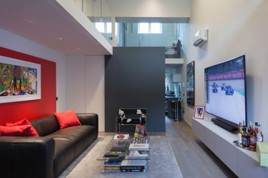 Esempio di un piccolo soggiorno minimal stile loft con pareti bianche, parquet scuro e TV a parete