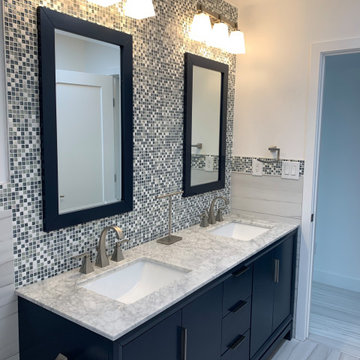 Hallway bathroom remodel with blue vanity and full backsplash tiled wall.