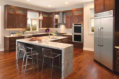 Design ideas for a large transitional u-shaped separate kitchen in Minneapolis with an undermount sink, shaker cabinets, dark wood cabinets, marble benchtops, beige splashback, porcelain splashback, stainless steel appliances, dark hardwood floors, with island and brown floor.