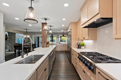 Eat-in kitchen - large transitional u-shaped dark wood floor and brown floor eat-in kitchen idea in Minneapolis with an undermount sink, shaker cabinets, brown cabinets, quartz countertops, white backsplash, quartz backsplash, stainless steel appliances, an island and white countertops