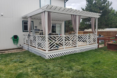 Ejemplo de terraza planta baja de estilo americano de tamaño medio en patio trasero con pérgola y barandilla de madera