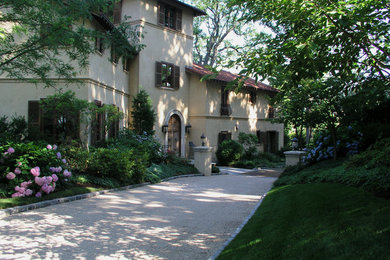 This is an example of a large mediterranean shade front yard gravel driveway in New York.