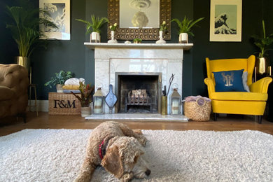 Large victorian grey and yellow enclosed living room in Sussex with green walls, medium hardwood flooring, a standard fireplace, a stone fireplace surround, a built-in media unit, a wallpapered ceiling and a chimney breast.