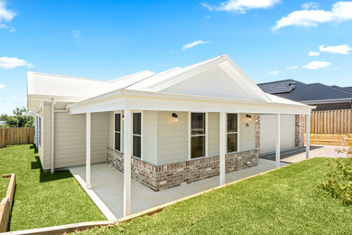 This is an example of a mid-sized country one-storey house exterior in Wollongong with a gable roof, a metal roof and a grey roof.