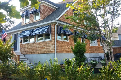 Example of a large beach style brown two-story wood house exterior design in New York with a shingle roof