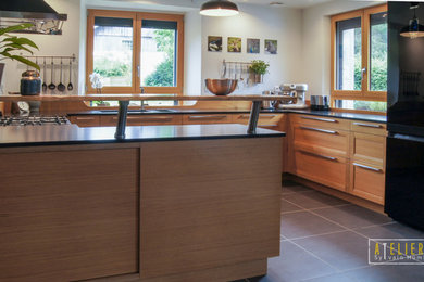 Photo of a medium sized rural u-shaped open plan kitchen in Marseille with a double-bowl sink, shaker cabinets, light wood cabinets, marble worktops, brown splashback, wood splashback, black appliances and an island.