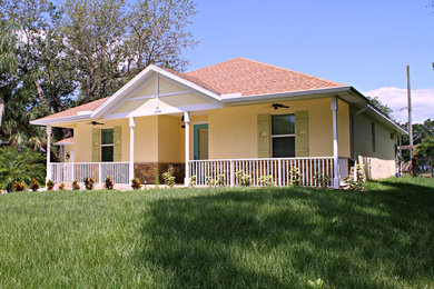 Large tropical one-storey yellow exterior in Tampa with mixed siding and a gable roof.