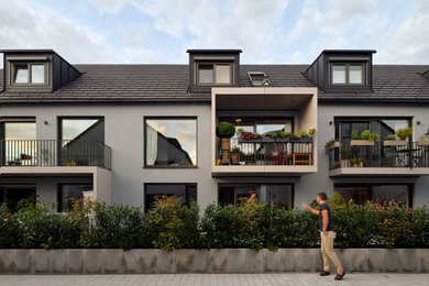 Große, Dreistöckige Moderne Doppelhaushälfte mit Betonfassade, bunter Fassadenfarbe, Satteldach und schwarzem Dach