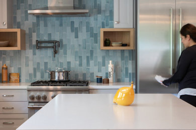 Example of a large tuscan l-shaped medium tone wood floor kitchen design in Los Angeles with an undermount sink, recessed-panel cabinets, blue backsplash, ceramic backsplash, stainless steel appliances, an island and white countertops