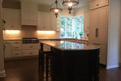 Open concept kitchen - large modern u-shaped medium tone wood floor open concept kitchen idea in Minneapolis with an undermount sink, raised-panel cabinets, white cabinets, granite countertops, beige backsplash, stone tile backsplash, paneled appliances and an island