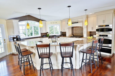 Inspiration for a huge contemporary u-shaped medium tone wood floor eat-in kitchen remodel in Philadelphia with an undermount sink, recessed-panel cabinets, white cabinets, quartz countertops, brown backsplash, ceramic backsplash, stainless steel appliances and an island