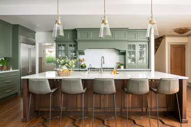 Eat-in kitchen - transitional medium tone wood floor and brown floor eat-in kitchen idea in Seattle with a drop-in sink, recessed-panel cabinets, green cabinets, white backsplash, stainless steel appliances, an island and white countertops