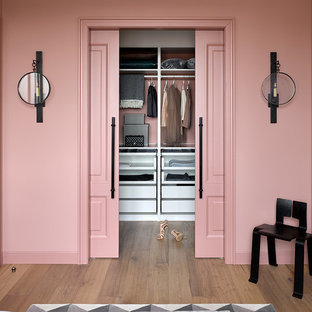 На фото: гардеробные комнаты в стиле современная классика с белыми фасадами, паркетным полом среднего тона, коричневым полом и открытыми фасадами для женщин