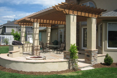 This is an example of a mid-sized traditional backyard patio in Denver with an outdoor kitchen, natural stone pavers and a pergola.