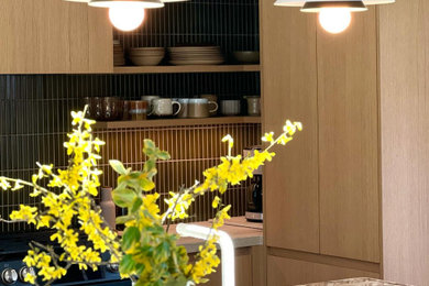 Mid-sized zen laminate floor and vaulted ceiling eat-in kitchen photo in Toronto with an undermount sink, flat-panel cabinets, granite countertops, green backsplash, ceramic backsplash, black appliances, an island and white countertops