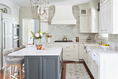 Example of a mid-sized transitional galley medium tone wood floor, brown floor and tray ceiling eat-in kitchen design in Chicago with a farmhouse sink, shaker cabinets, white cabinets, quartzite countertops, white backsplash, subway tile backsplash, white appliances, an island and white countertops