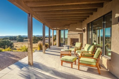 Example of a large southwest front yard patio design in Albuquerque with a fire pit and a roof extension