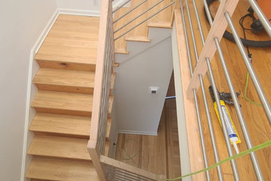 Ejemplo de escalera en L minimalista de tamaño medio con escalones de madera, contrahuellas de madera y barandilla de varios materiales