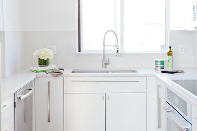 Kitchen - mid-sized contemporary dark wood floor kitchen idea in Vancouver with a double-bowl sink, white cabinets, white backsplash and stainless steel appliances