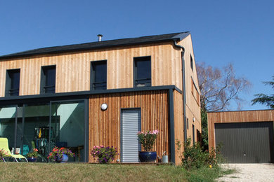 Idée de décoration pour une grande façade de maison marron design en bois à un étage avec un toit à deux pans et un toit en métal.