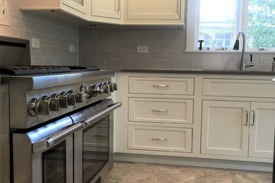Large elegant l-shaped marble floor enclosed kitchen photo in Chicago with a double-bowl sink, shaker cabinets, white cabinets, quartzite countertops, gray backsplash, subway tile backsplash, stainless steel appliances, an island and black countertops