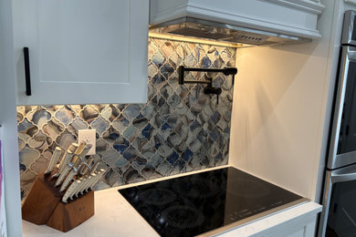 Minimalist kitchen photo in Other with white cabinets, multicolored backsplash, glass tile backsplash, an island and white countertops
