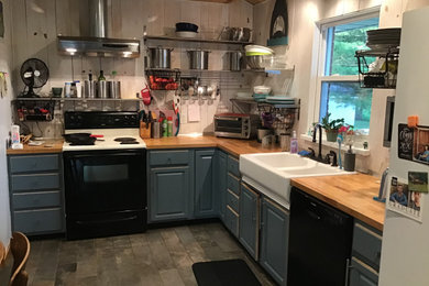 Mid-sized trendy l-shaped ceramic tile and gray floor eat-in kitchen photo in St Louis with a farmhouse sink, flat-panel cabinets, blue cabinets, wood countertops, white backsplash, wood backsplash, black appliances, an island and multicolored countertops