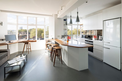 This is an example of a contemporary open plan kitchen in London with an undermount sink, flat-panel cabinets, white cabinets, mirror splashback, linoleum floors, a peninsula, grey floor and white appliances.