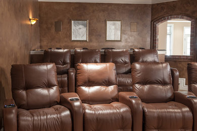 Inspiration for a mid-sized mediterranean enclosed home theatre in St Louis with brown walls, carpet, a projector screen and beige floor.