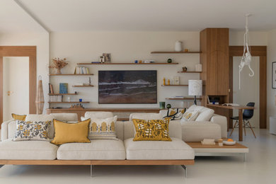Cette image montre un très grand salon blanc et bois design ouvert avec une bibliothèque ou un coin lecture, un mur blanc, sol en béton ciré, un téléviseur fixé au mur et un sol blanc.