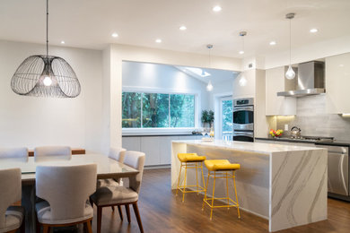 Inspiration for a mid-sized contemporary medium tone wood floor and brown floor eat-in kitchen remodel in New York with an undermount sink, flat-panel cabinets, gray cabinets, gray backsplash, ceramic backsplash, stainless steel appliances, an island, black countertops and quartz countertops