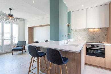 Idée de décoration pour une très grande cuisine ouverte design en L avec un évier encastré, un placard à porte affleurante, des portes de placard blanches, un plan de travail en stratifié, une crédence blanche, un électroménager en acier inoxydable, îlot, un sol gris et un plan de travail blanc.