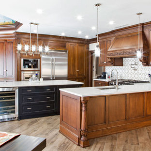 Design ideas for a large traditional u-shaped eat-in kitchen in New York with a drop-in sink, shaker cabinets, medium wood cabinets, quartz benchtops, white splashback, engineered quartz splashback, stainless steel appliances, light hardwood floors, with island, brown floor, white benchtop and wallpaper.