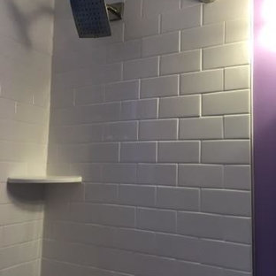 Foto di una piccola stanza da bagno con doccia moderna con ante lisce, ante nere, vasca/doccia, pareti viola, vasca ad angolo, WC monopezzo, pavimento in legno verniciato, lavabo da incasso e top in superficie solida